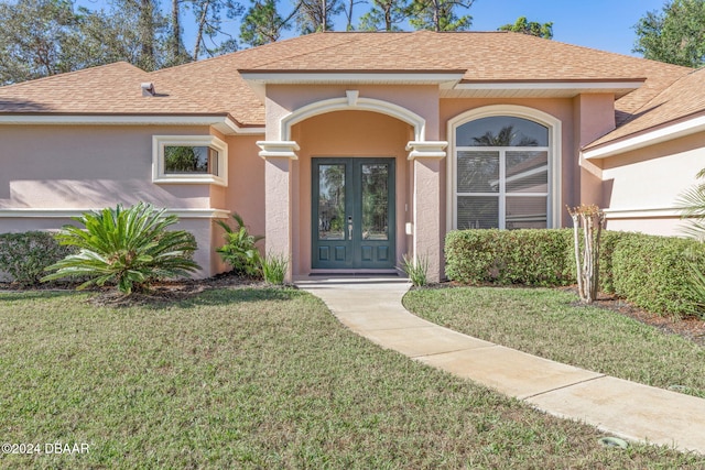 3404 Rexford Cir, Ormond Beach, FL 32174 - view of exterior entry featuring french doors, stucco siding, a yard, and roof with shingles