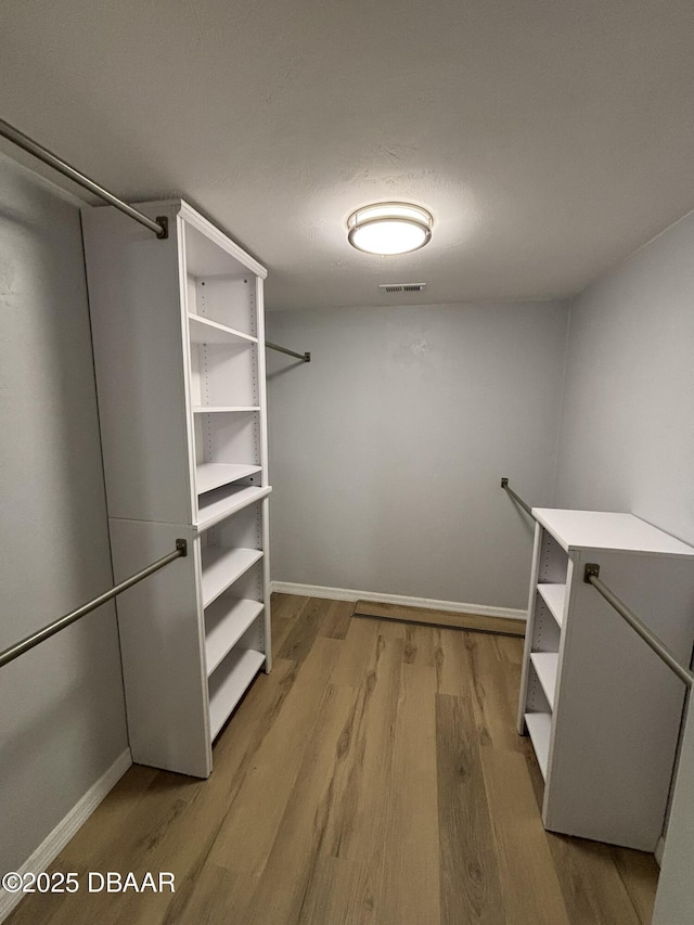 walk in closet with light wood finished floors and visible vents