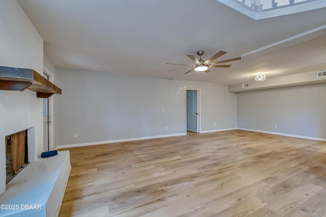 unfurnished living room featuring light wood-type flooring, baseboards, a fireplace with raised hearth, and a ceiling fan