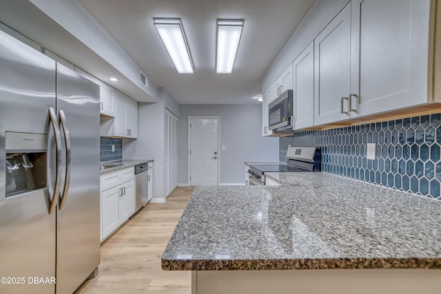 kitchen featuring stainless steel appliances, stone countertops, white cabinets, and light wood-type flooring