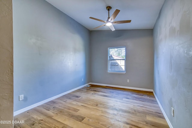 empty room featuring vaulted ceiling, light wood finished floors, a ceiling fan, and baseboards