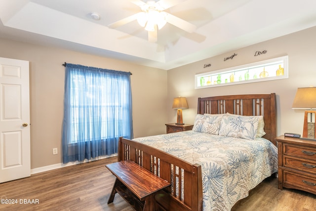 bedroom featuring hardwood / wood-style floors, ceiling fan, and a raised ceiling