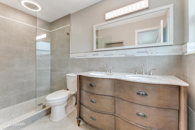 bathroom with toilet, a tile shower, tasteful backsplash, tile walls, and vanity