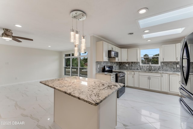 kitchen featuring white cabinetry, a center island, hanging light fixtures, black appliances, and sink