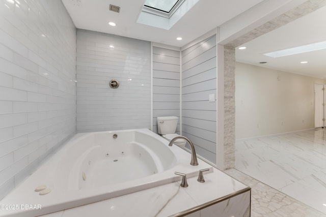 bathroom featuring a bath, toilet, and a skylight