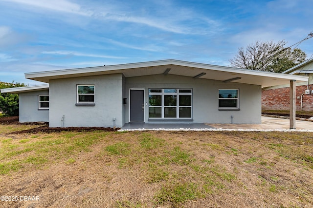 back of property featuring a patio area and a lawn