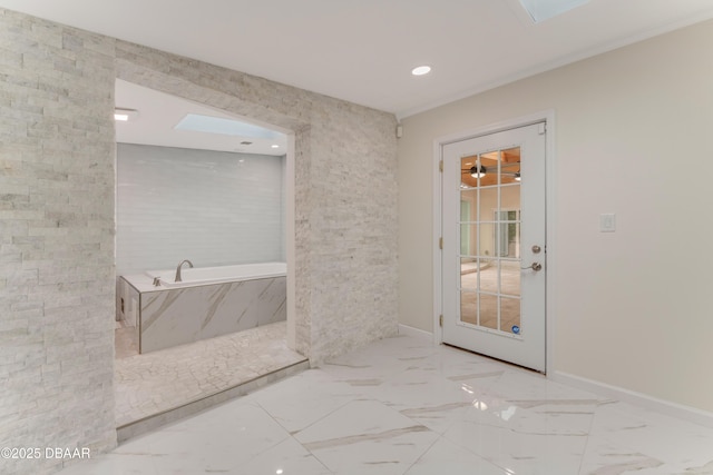 bathroom featuring a skylight and a relaxing tiled tub