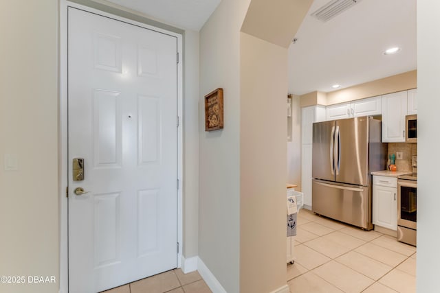 kitchen featuring white cabinetry, stainless steel appliances, tasteful backsplash, and light tile patterned floors