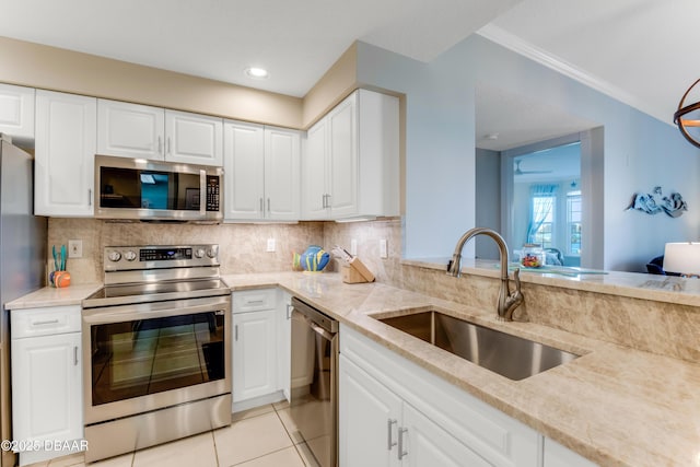 kitchen with sink, backsplash, white cabinets, light stone counters, and stainless steel appliances