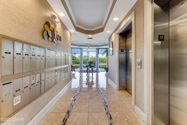 corridor with elevator, ornamental molding, a tray ceiling, and mail boxes