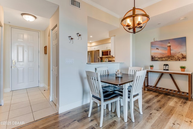 dining room featuring crown molding, light wood-type flooring, and a chandelier