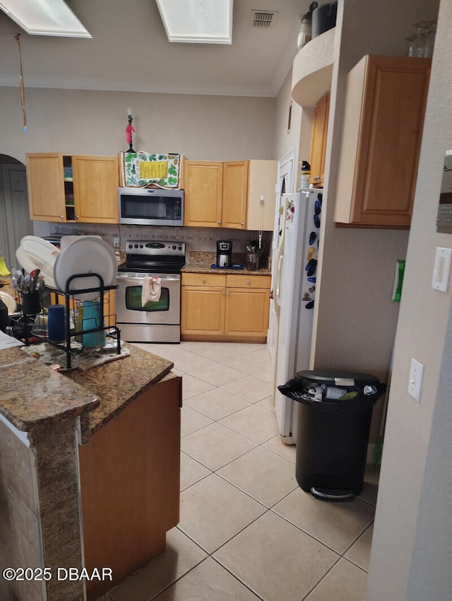 kitchen featuring light tile patterned floors, visible vents, backsplash, appliances with stainless steel finishes, and dark stone counters