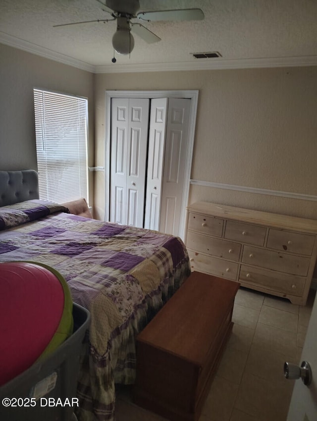 bedroom featuring a closet, visible vents, ornamental molding, ceiling fan, and a textured ceiling