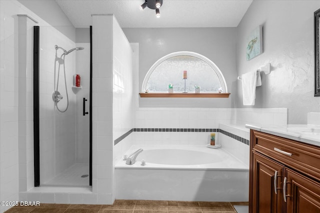 bathroom with a textured ceiling, tile patterned floors, plus walk in shower, and vanity