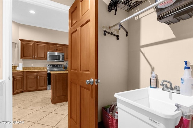 interior space featuring light tile patterned floors, appliances with stainless steel finishes, crown molding, and sink