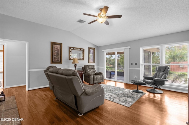 living room featuring lofted ceiling, plenty of natural light, a textured ceiling, and hardwood / wood-style floors