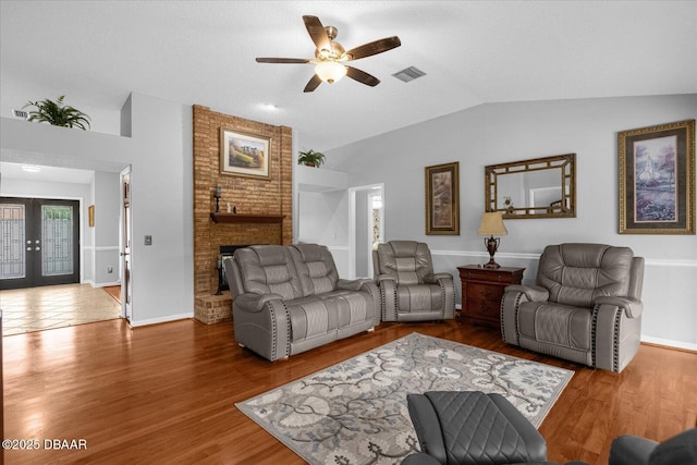 living room featuring ceiling fan, vaulted ceiling, a fireplace, hardwood / wood-style flooring, and french doors