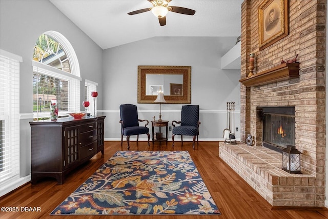 sitting room with a fireplace, vaulted ceiling, dark wood-type flooring, and ceiling fan