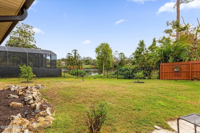 view of yard with a water view and glass enclosure