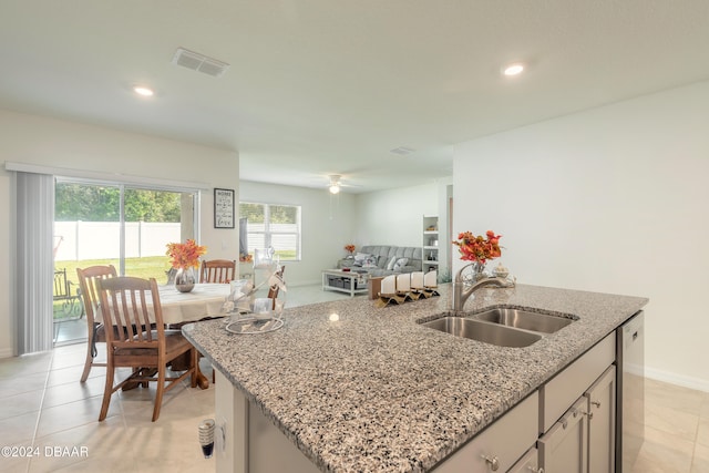 kitchen featuring an island with sink, light stone countertops, light tile patterned floors, and sink