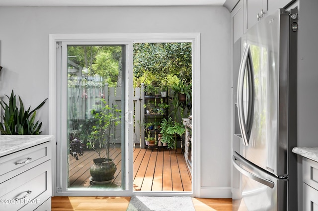 doorway with baseboards, a wealth of natural light, and light wood-type flooring