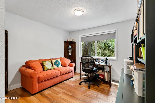 office area featuring light wood-style floors, a textured ceiling, and baseboards