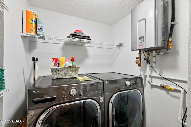 washroom with laundry area, washer and clothes dryer, a textured ceiling, and water heater