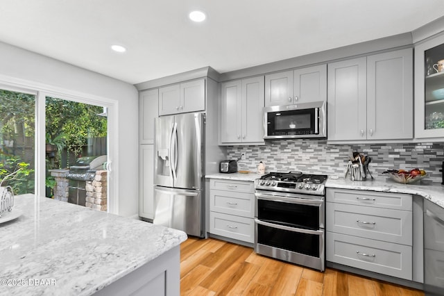 kitchen with light stone countertops, stainless steel appliances, recessed lighting, tasteful backsplash, and gray cabinetry