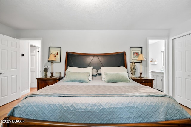 bedroom with ensuite bathroom and light wood finished floors