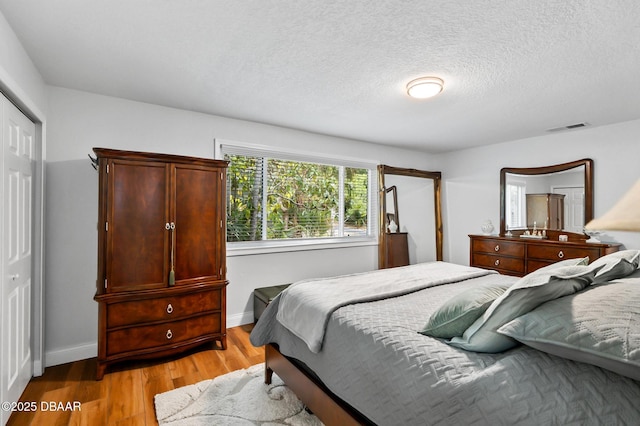 bedroom featuring baseboards, visible vents, light wood-style flooring, and a closet