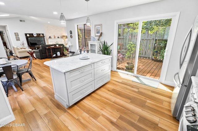 kitchen featuring hanging light fixtures, light stone countertops, light wood-type flooring, stainless steel refrigerator, and recessed lighting
