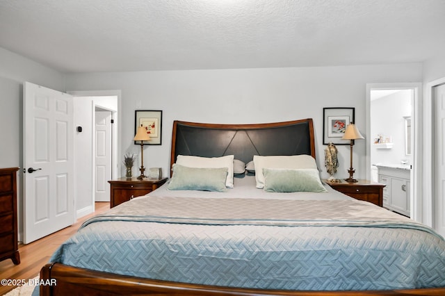 bedroom with connected bathroom and light wood-style flooring