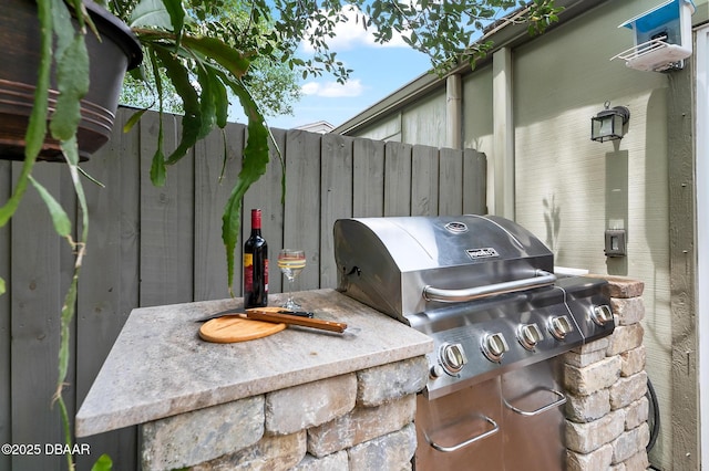 view of patio with fence and a grill