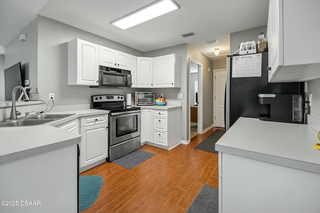 kitchen with sink, white cabinetry, light hardwood / wood-style flooring, and stainless steel range with electric cooktop