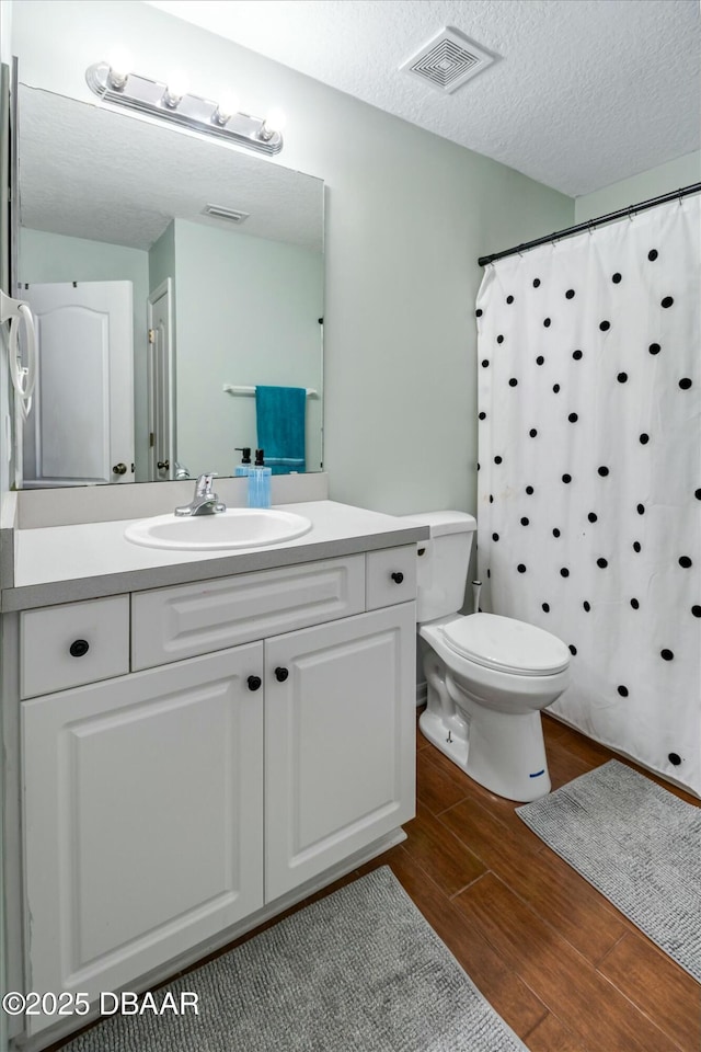 bathroom with a textured ceiling, toilet, a shower with curtain, and vanity