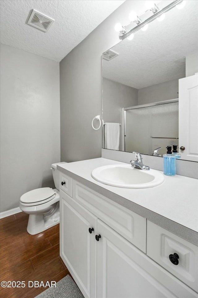 bathroom with vanity, toilet, a textured ceiling, and walk in shower