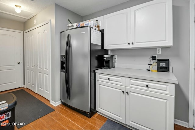 kitchen featuring stainless steel fridge and white cabinetry