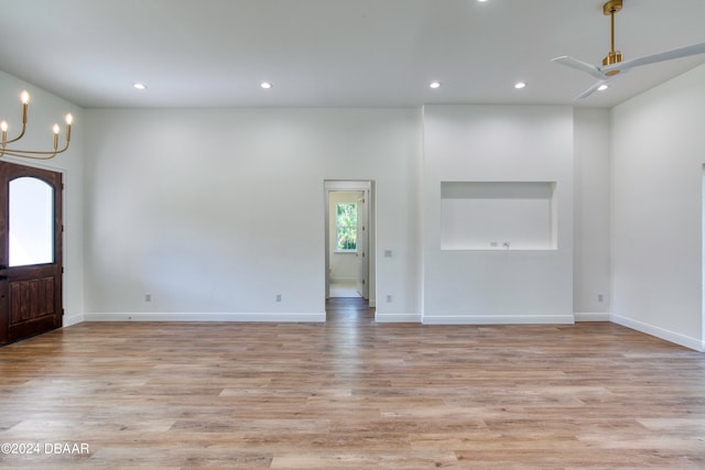 empty room featuring light wood-type flooring and ceiling fan with notable chandelier