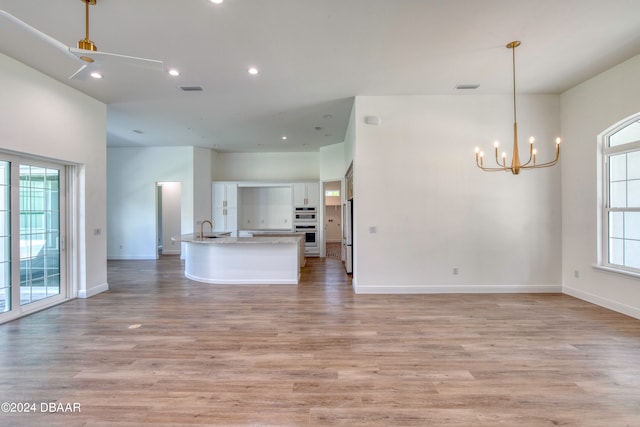 kitchen with white cabinetry, light hardwood / wood-style floors, hanging light fixtures, and sink