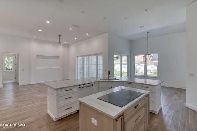 kitchen with white cabinets, black electric stovetop, a healthy amount of sunlight, and a center island