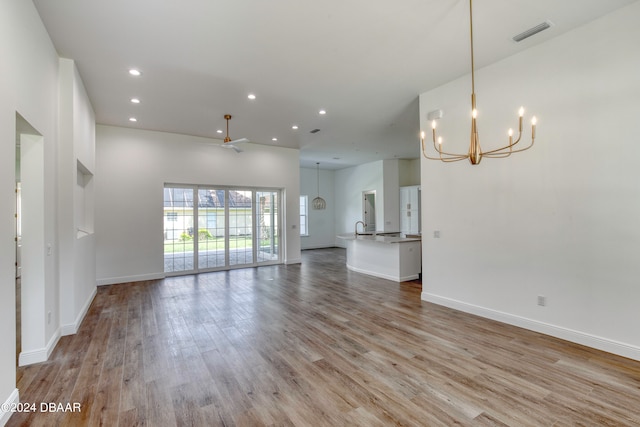 unfurnished living room featuring ceiling fan with notable chandelier, sink, and light hardwood / wood-style flooring