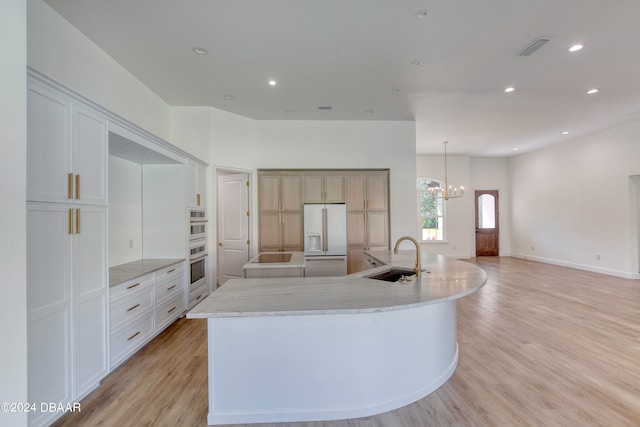 kitchen featuring light hardwood / wood-style floors, sink, white refrigerator with ice dispenser, and a spacious island