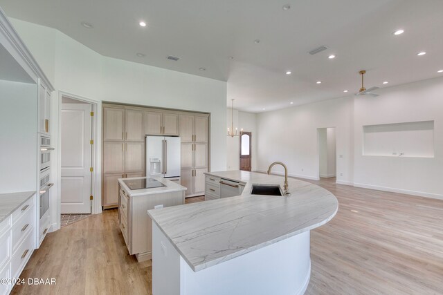 kitchen with stainless steel appliances, light hardwood / wood-style floors, sink, pendant lighting, and a large island with sink