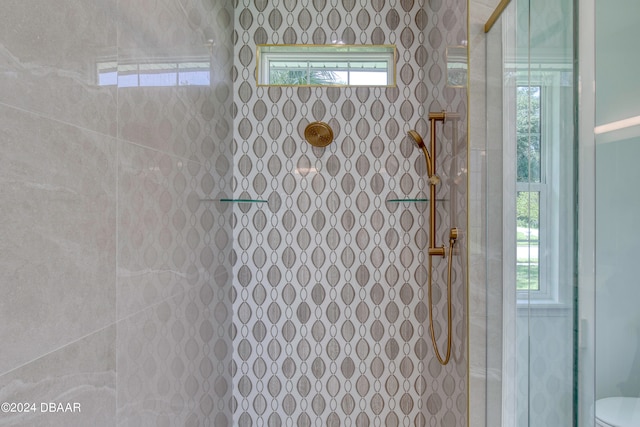 bathroom featuring a wealth of natural light, toilet, and a tile shower