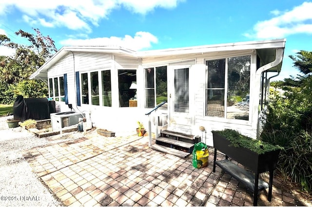 rear view of property with entry steps and a patio