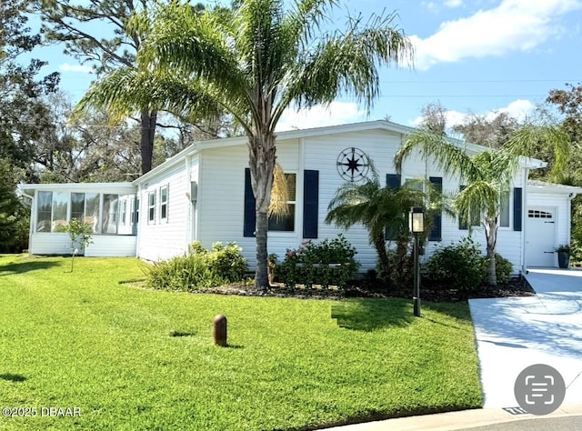 view of front of house featuring a garage, a front lawn, and a sunroom