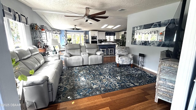 living area featuring visible vents, lofted ceiling, ceiling fan, wood finished floors, and a textured ceiling