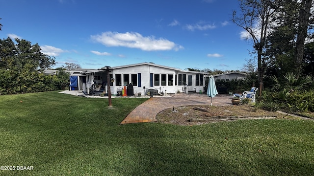 rear view of house featuring a sunroom, a patio, and a lawn