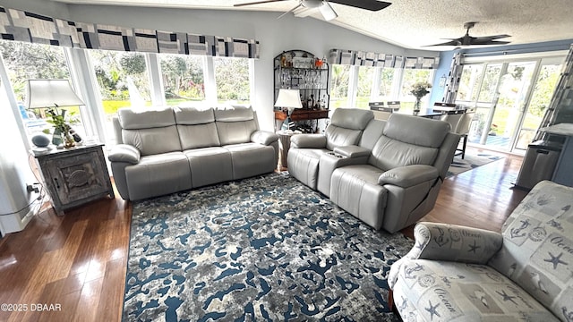 living area featuring ceiling fan, vaulted ceiling, a textured ceiling, and wood finished floors