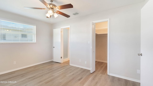 unfurnished bedroom featuring a walk in closet, ceiling fan, a closet, and light hardwood / wood-style floors